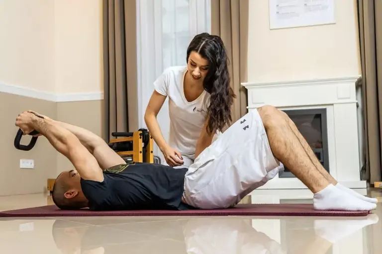 Gyógytornász segít egy matracon fekvő páciensnek lábgyakorlat közben